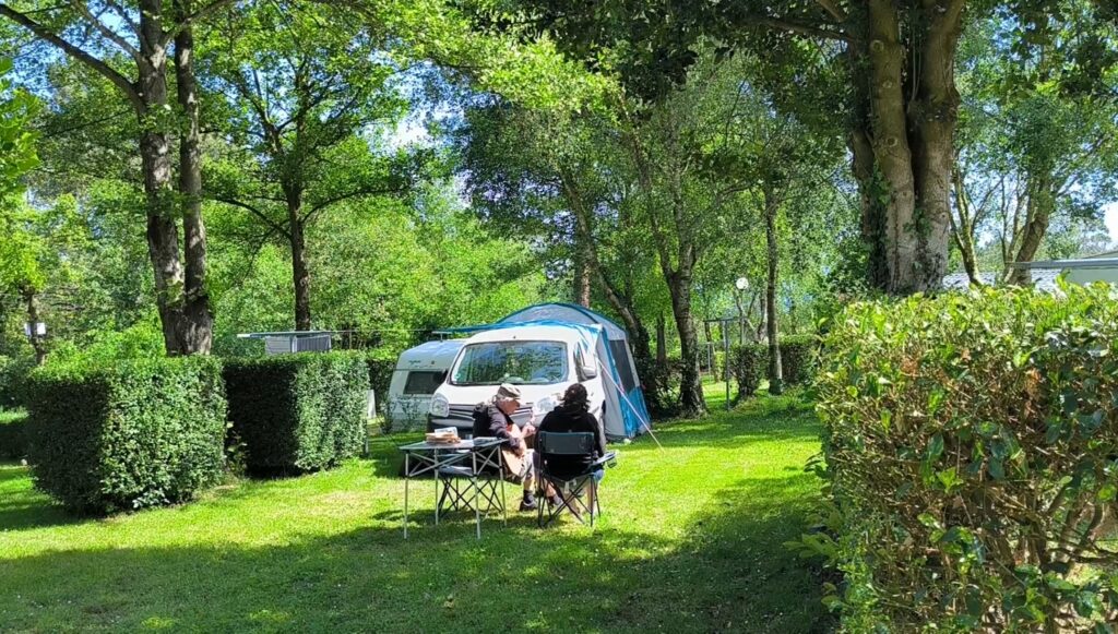 Dos personas tocando música disfrutando del paisaje en el camping playa de otur